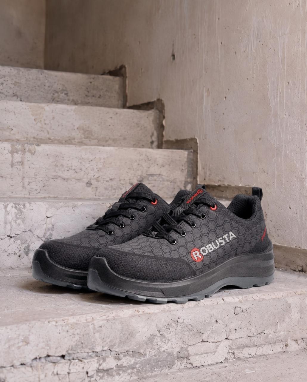 Par de tenis de seguridad negros sobre escalones de concreto